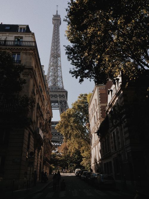 Free Charming urban view of the Eiffel Tower framed by classic Parisian architecture and street. Stock Photo