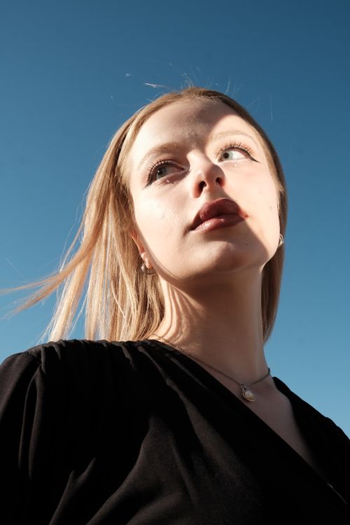 Free Close-up of a sunlit woman with blonde hair against a clear blue sky. Stock Photo