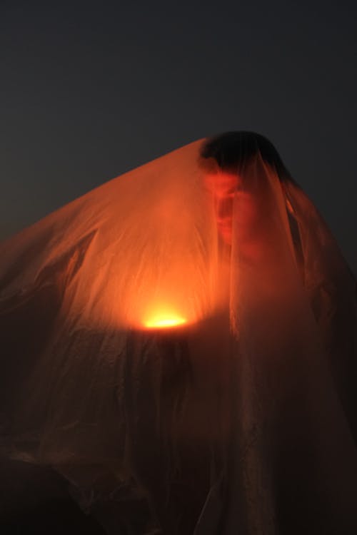 A Man Standing under See-through Fabric with a Light