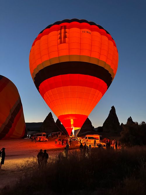 Free Hot air balloon illuminated against Cappadocia rock formations at sunrise, perfect for travel inspiration. Stock Photo