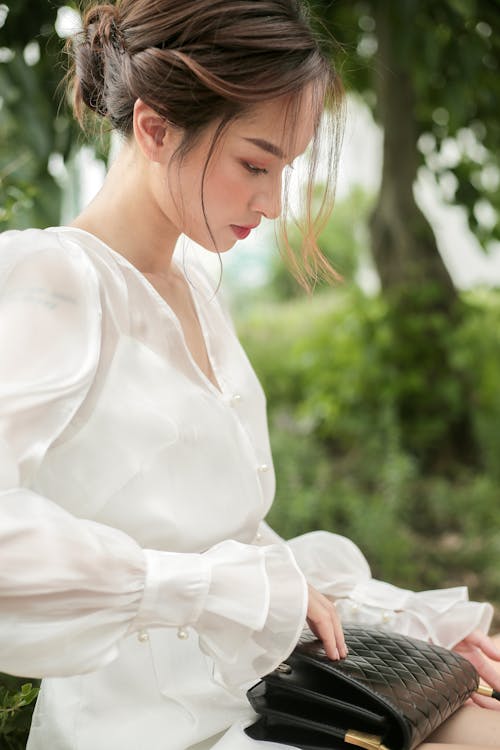 Young Elegant Woman in a White Dress Sitting Outside