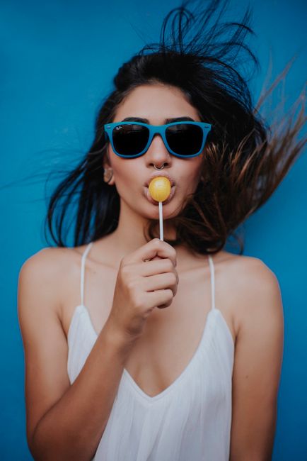 Trendy portrait of a stylish young woman enjoying a lollipop in summer.