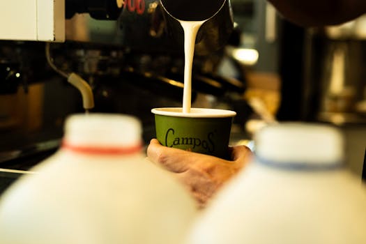 Close-up of barista pouring milk into a cup at a cafe. Captured with X-T5.