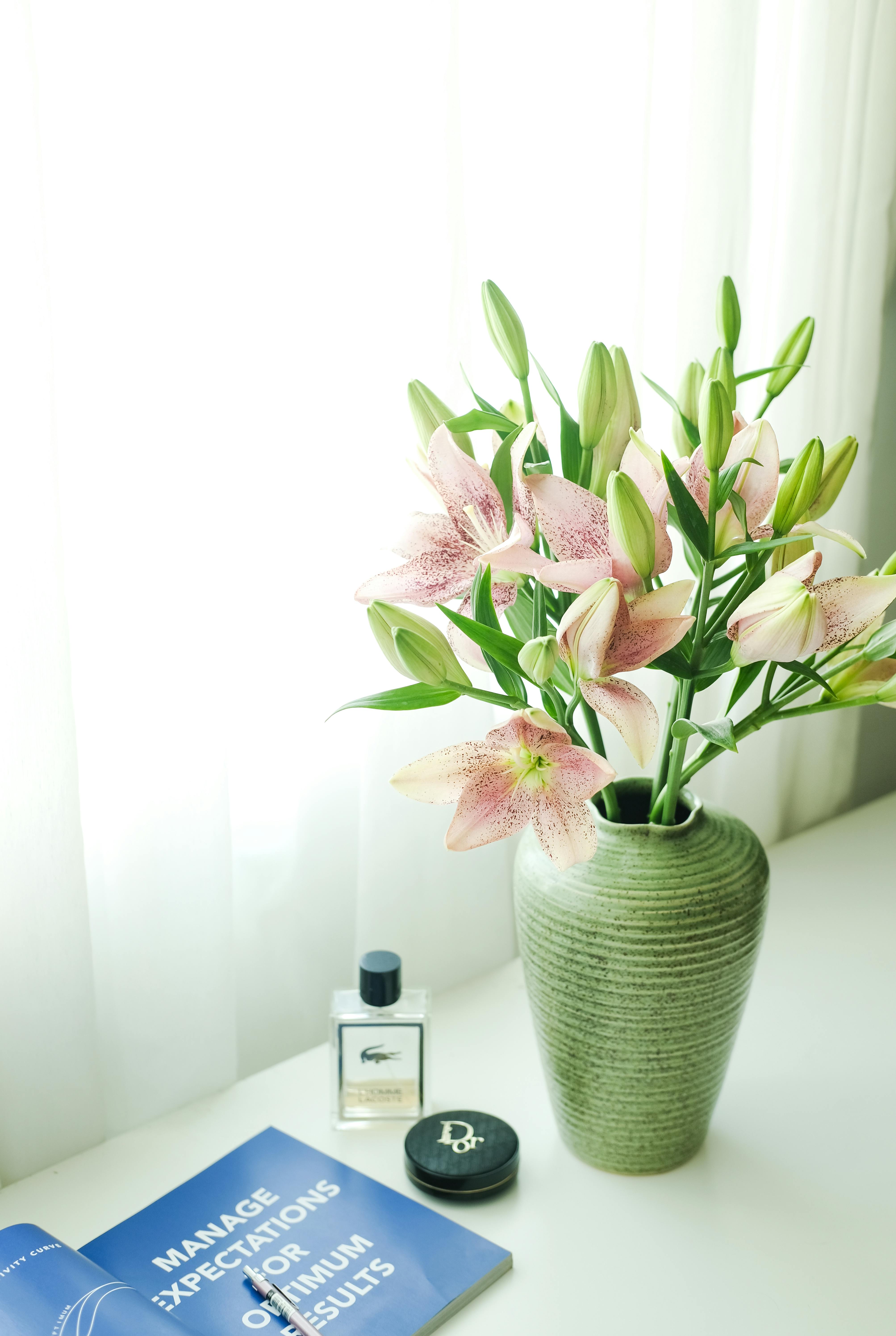 Aesthetic floral display with lilies in a green vase, enhancing interior decor.