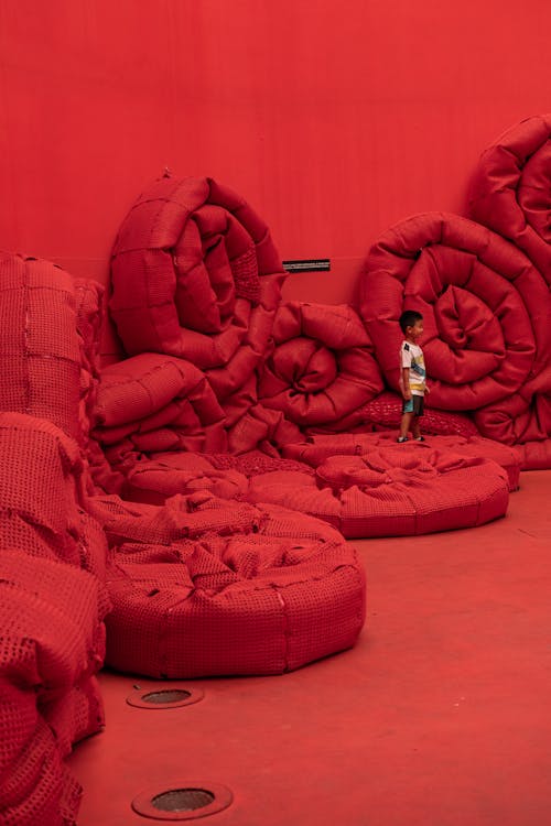 Little Boy on Rolls of Recycled Plastic Crochet Mesh of Artistic Installation at Milan Design Week