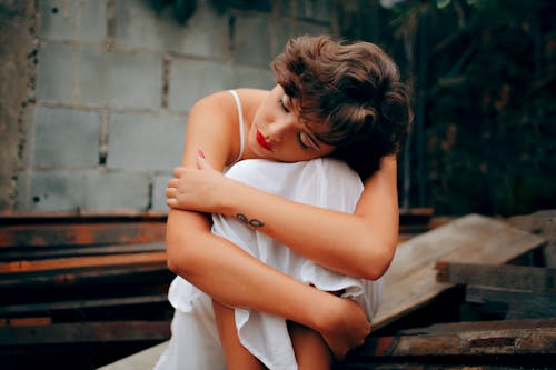 Free Woman Squatting Near Gray Concrete Wall Stock Photo