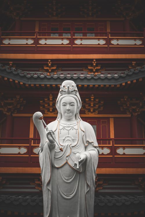Free Explore the serene beauty of a Guanyin statue in front of an ornate Asian temple. Stock Photo