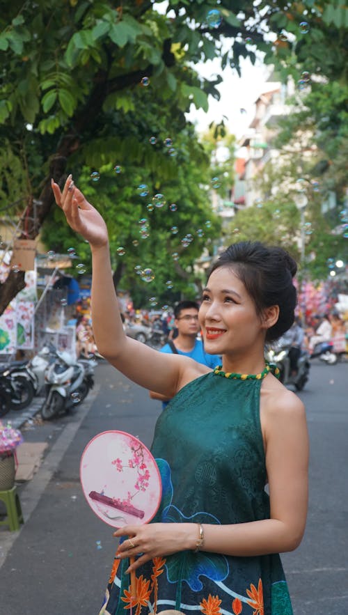 Young Woman With a Paper Fan Trying to Catch Soap Bubbles