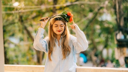 Young Woman Holding a Bouquet of Roses on Her Head