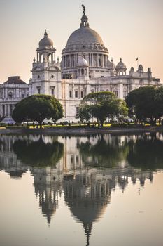 Elegant view of Victoria Memorial reflecting in tranquil water at sunset in Kolkata, India.