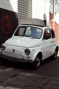 Classic white Fiat 500 parked on a street in Catania, Sicily, exuding nostalgia and charm.