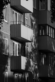 Monochrome image of apartment building with balconies casting shadows, creating an urban feel.