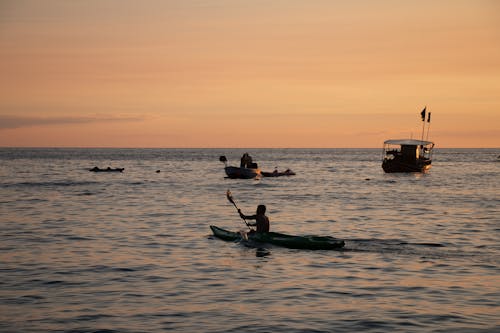 Tourists in Boats and Kayaks on the Sea at Sunset