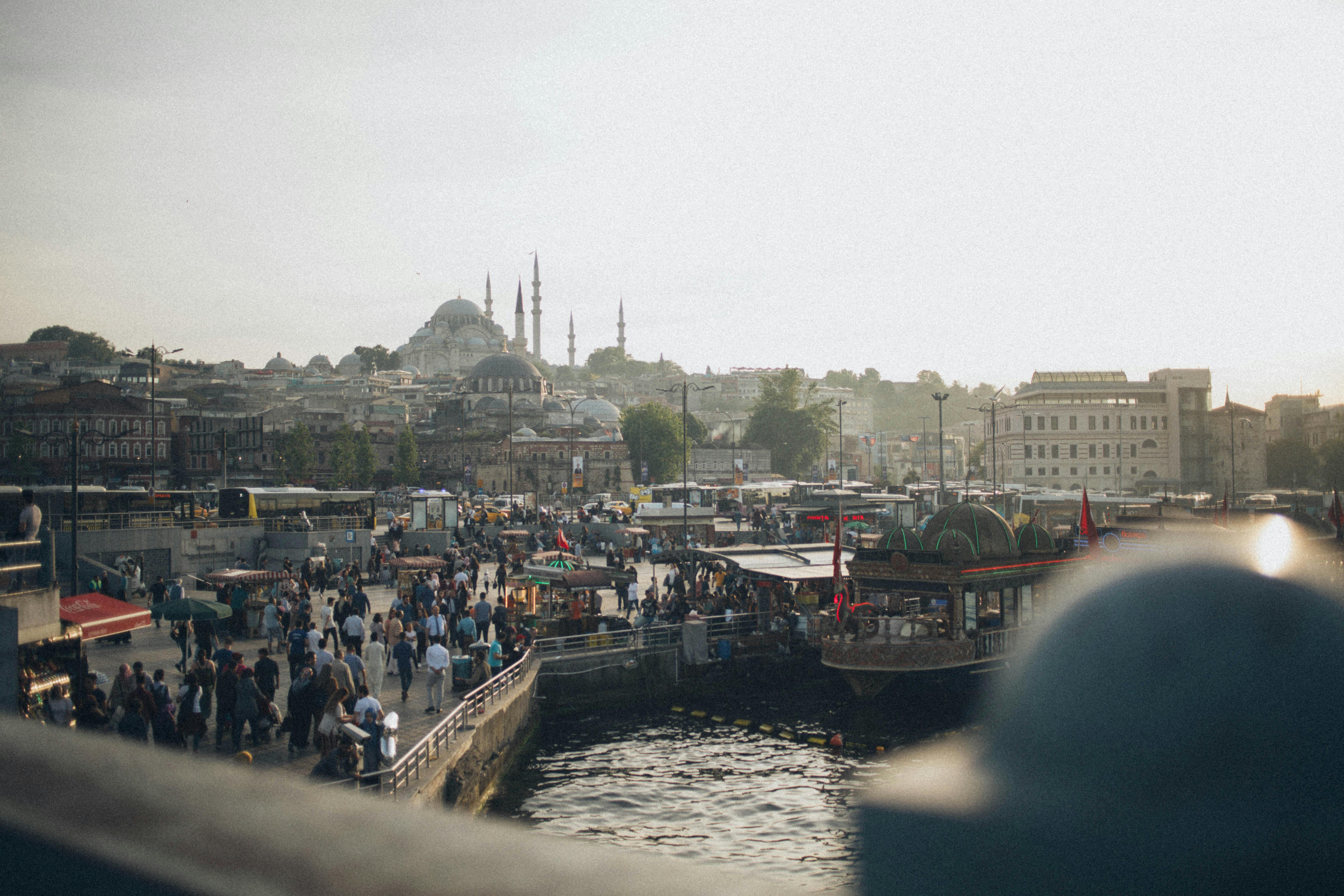 伊斯坦布尔海滨充满活力，人群熙熙攘攘，标志性的清真寺沐浴在日落氛围中