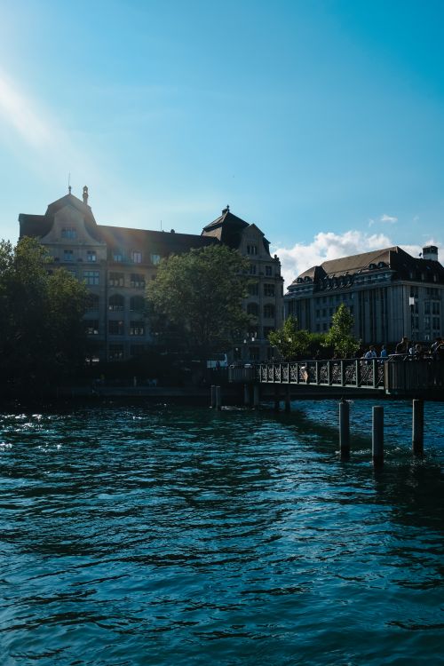 Free Picturesque Zurich scene featuring Limmat River with classic architecture and a bridge under clear blue skies. Stock Photo
