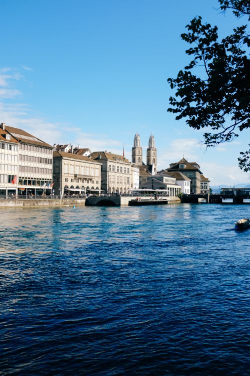 Free Scenic view of Zurich's historic buildings along the Limmat River under a clear blue sky. Stock Photo