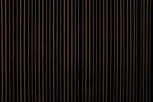 A close-up view of an abstract pattern with vertical gold and black stripes, creating a textured design.
