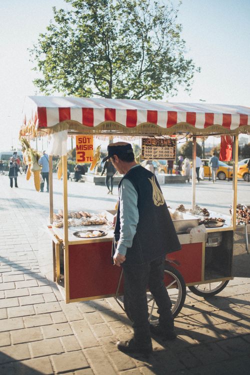 Free A street vendor sells snacks from a cart in an outdoor market on a sunny day. Stock Photo