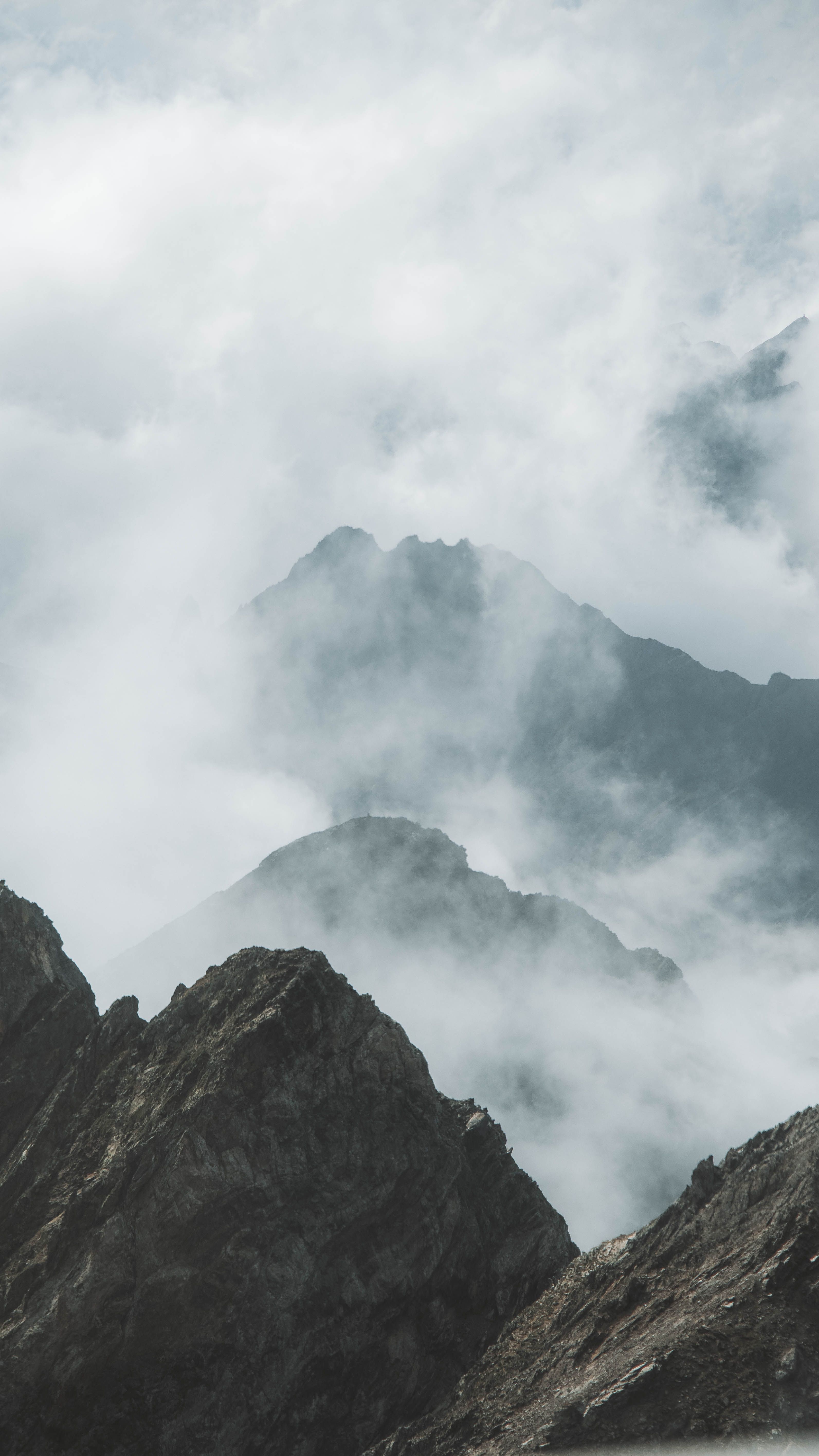 A breathtaking view of mountain peaks shrouded in mist and clouds, capturing nature's beauty.