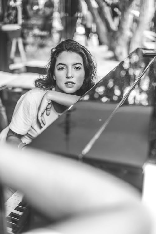 Greyscale Photo Of Woman Leaning On Piano