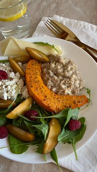 Deliciously plated pumpkin and arugula salad with fruit and cheese.