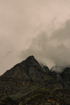 Gloomy mountain peak shrouded in misty clouds in Himachal Pradesh, India.
