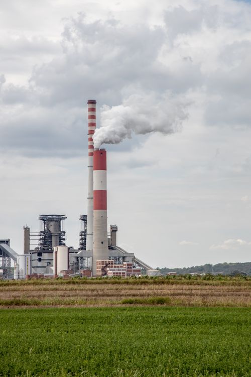 Free Power station with smoking chimneys in a green field, showcasing environmental impact. Stock Photo