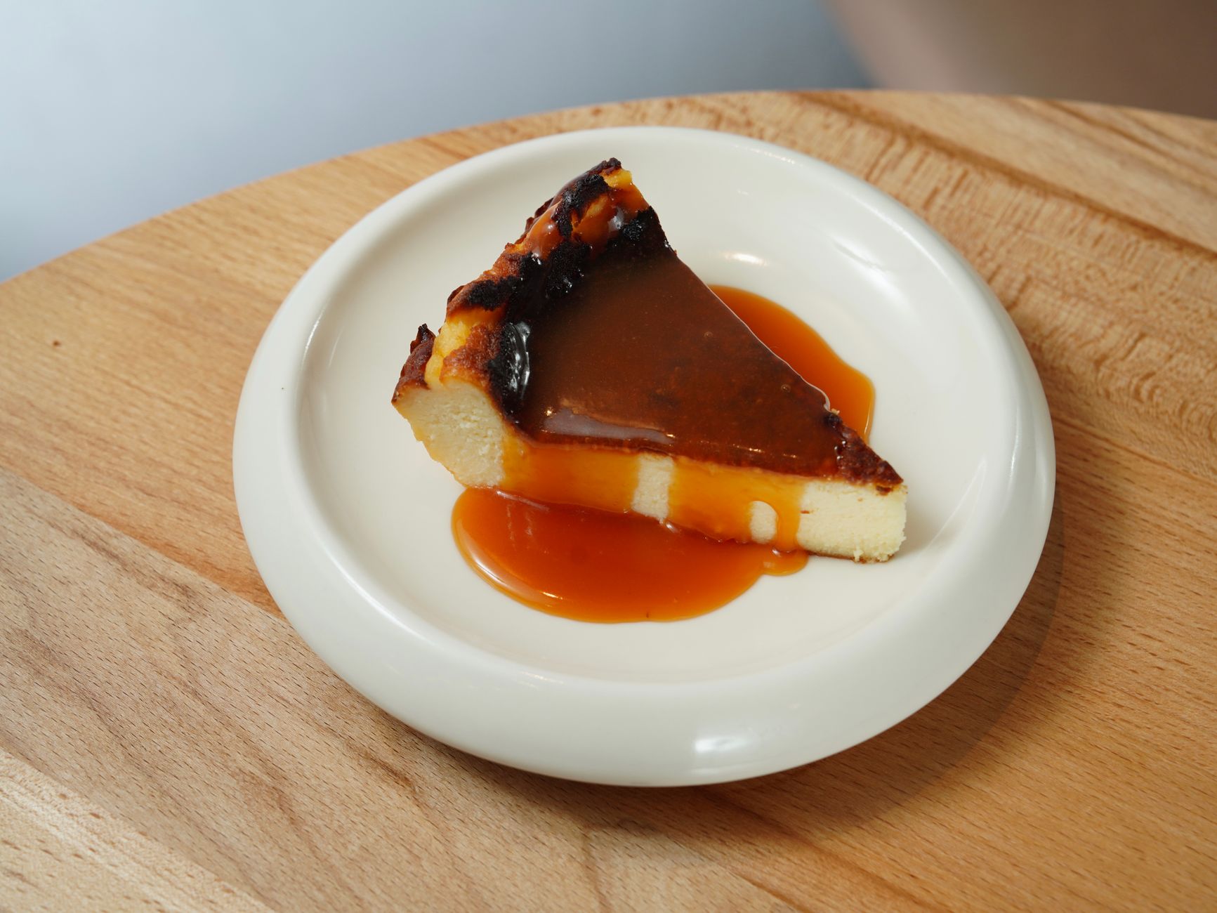 Slice of burnt Basque cheesecake with rich creamy texture on white plate