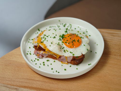 Foto de stock gratuita de plato con sándwich Croque Madame sobre una mesa de madera