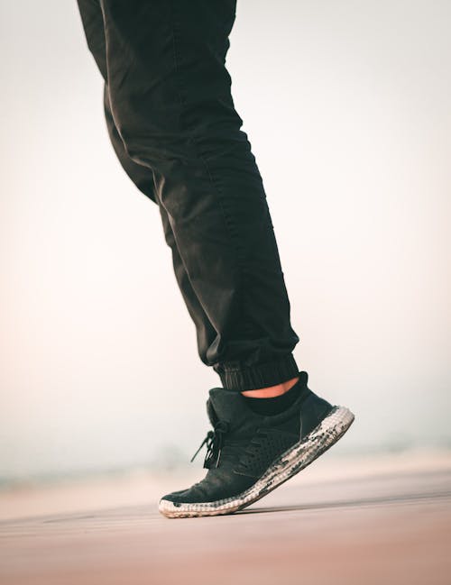 Person in Black Sneakers Standing on Tiptoe