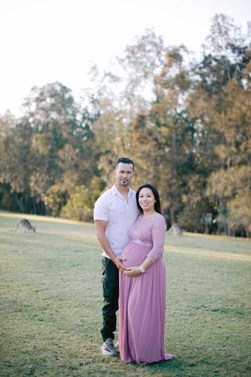 Pregnant Woman and Man Posing on a Lawn