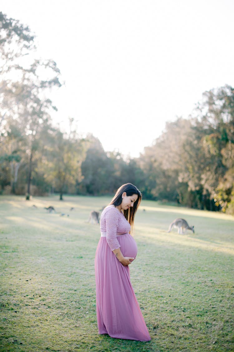 Pregnant Woman Posing Outside And Touching Her Stomach 