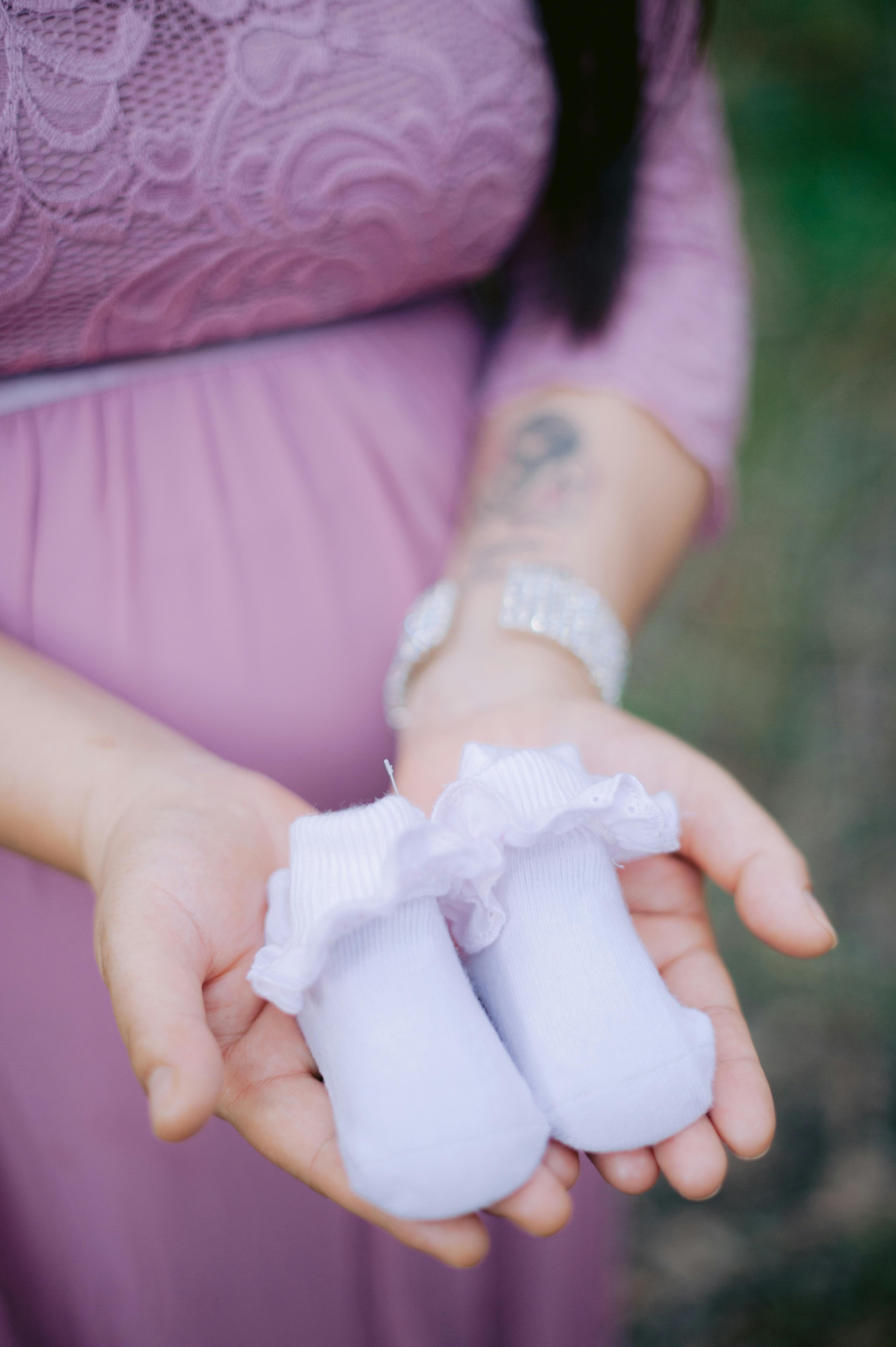 pregnant woman holding tiny baby shoes