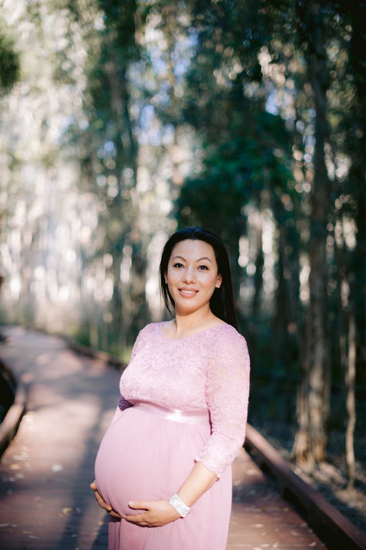 Pregnant Woman Posing Outside And Touching Her Stomach 