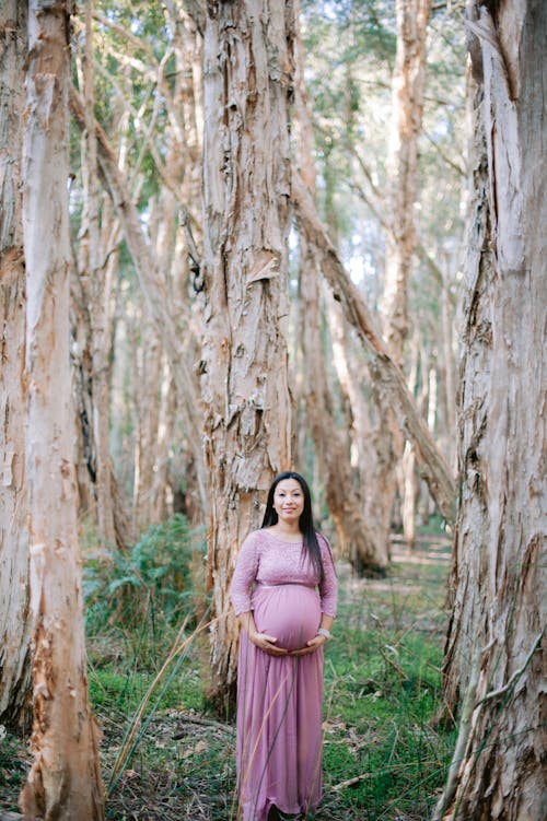Woman in Maternity Dress Standing in the Forest
