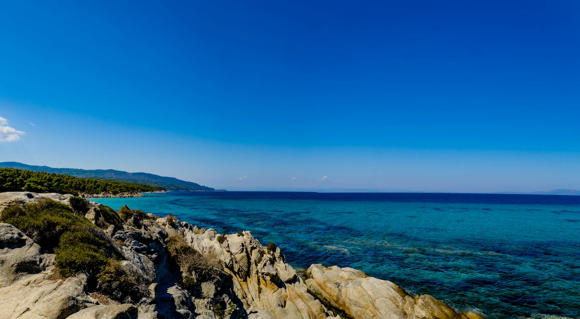 Stunning rocky coastline with vivid blue waters under a clear sky, ideal for travel and nature imagery.