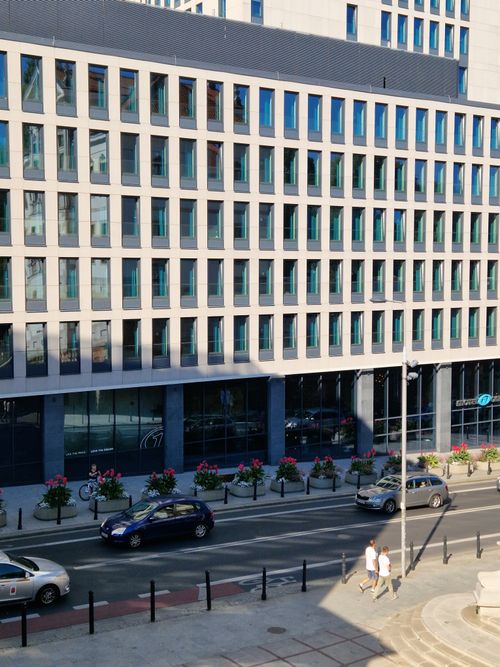 Free Contemporary office building in Warsaw city center with cars passing by. Stock Photo