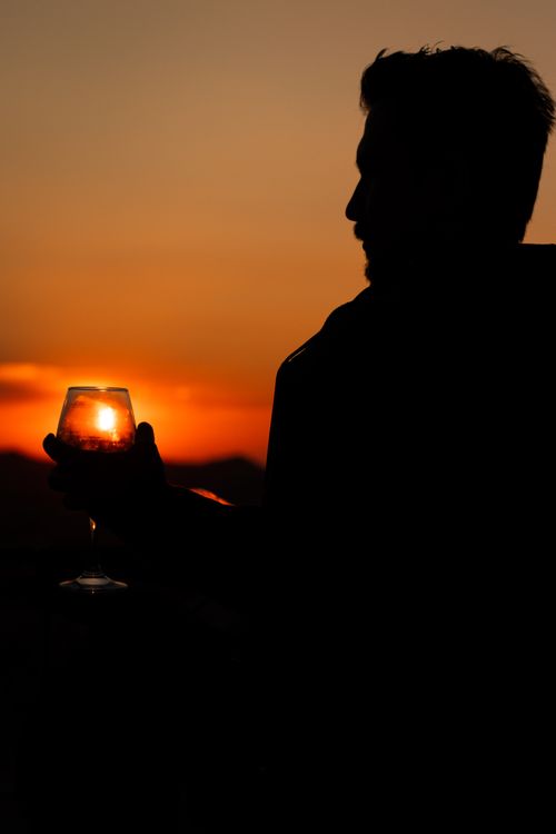 Free Silhouette of a man holding a wineglass against a stunning sunset in Ürgüp, Türkiye. Stock Photo