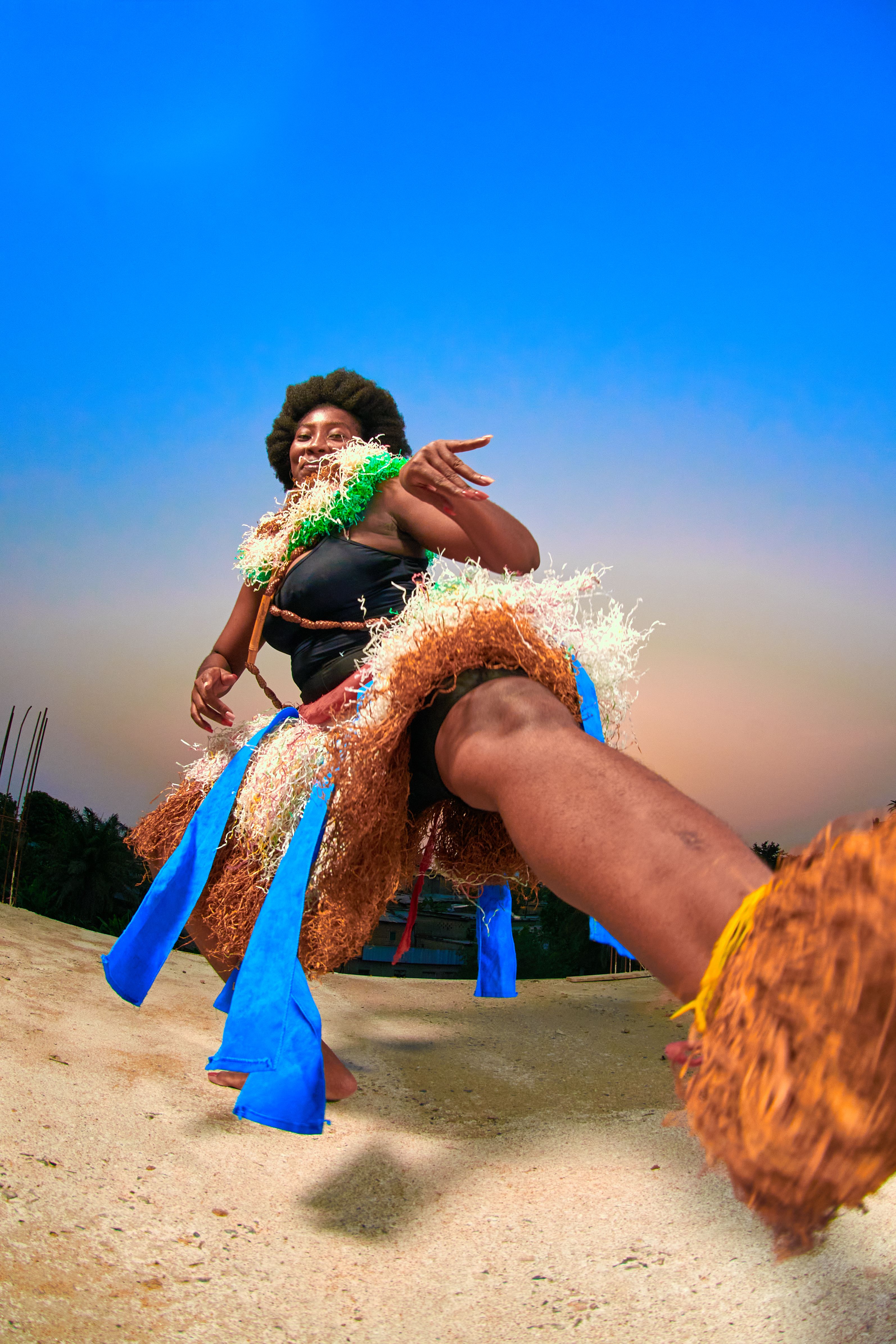 Energetic dancer performing in colorful traditional attire at sunset outdoors.