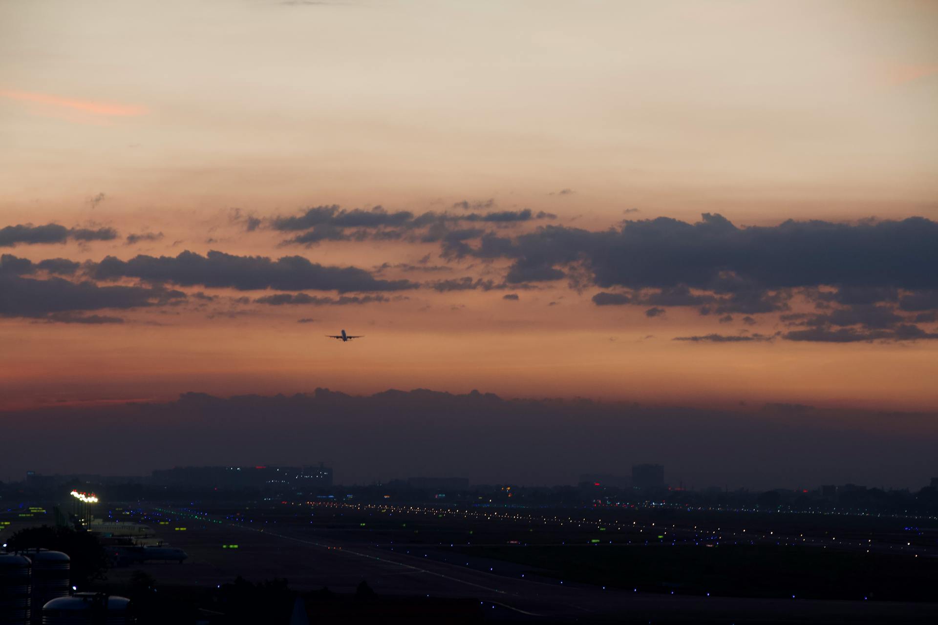 A serene view of an airplane taking off at sunrise over Ho Chi Minh City airport with a colorful sky.