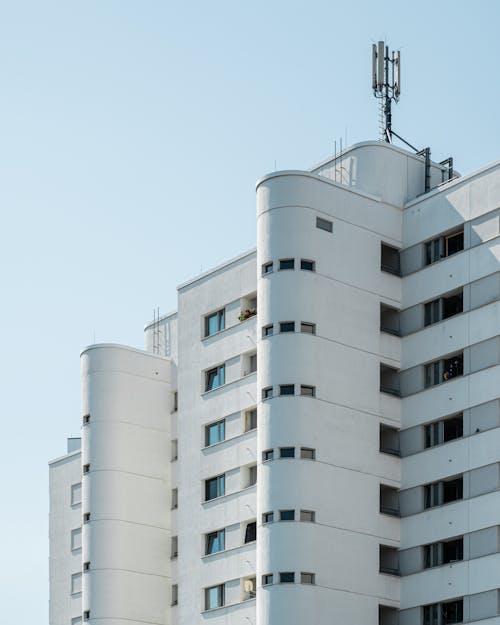 A tall white building with a cell phone tower on top