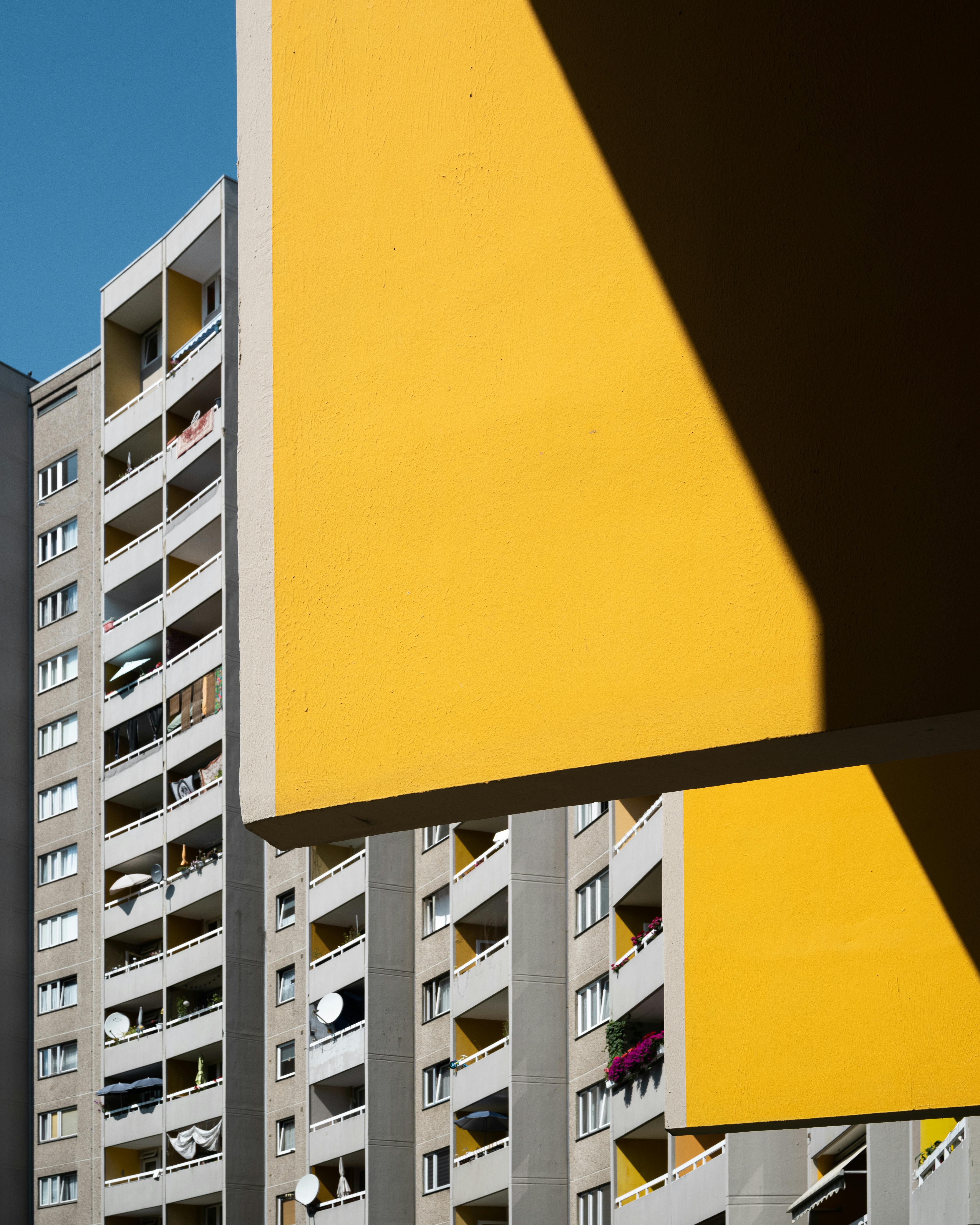 Contemporary buildings with bold yellow accents under clear blue skies in an urban setting.