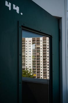 A high-rise building reflected in a glass window, showcasing urban architecture.