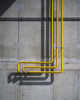 Vertical yellow pipes casting shadows on a rugged concrete wall in Berlin.