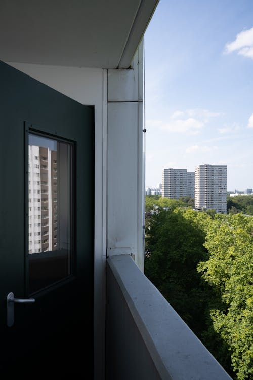 A view of a balcony with a green door and trees