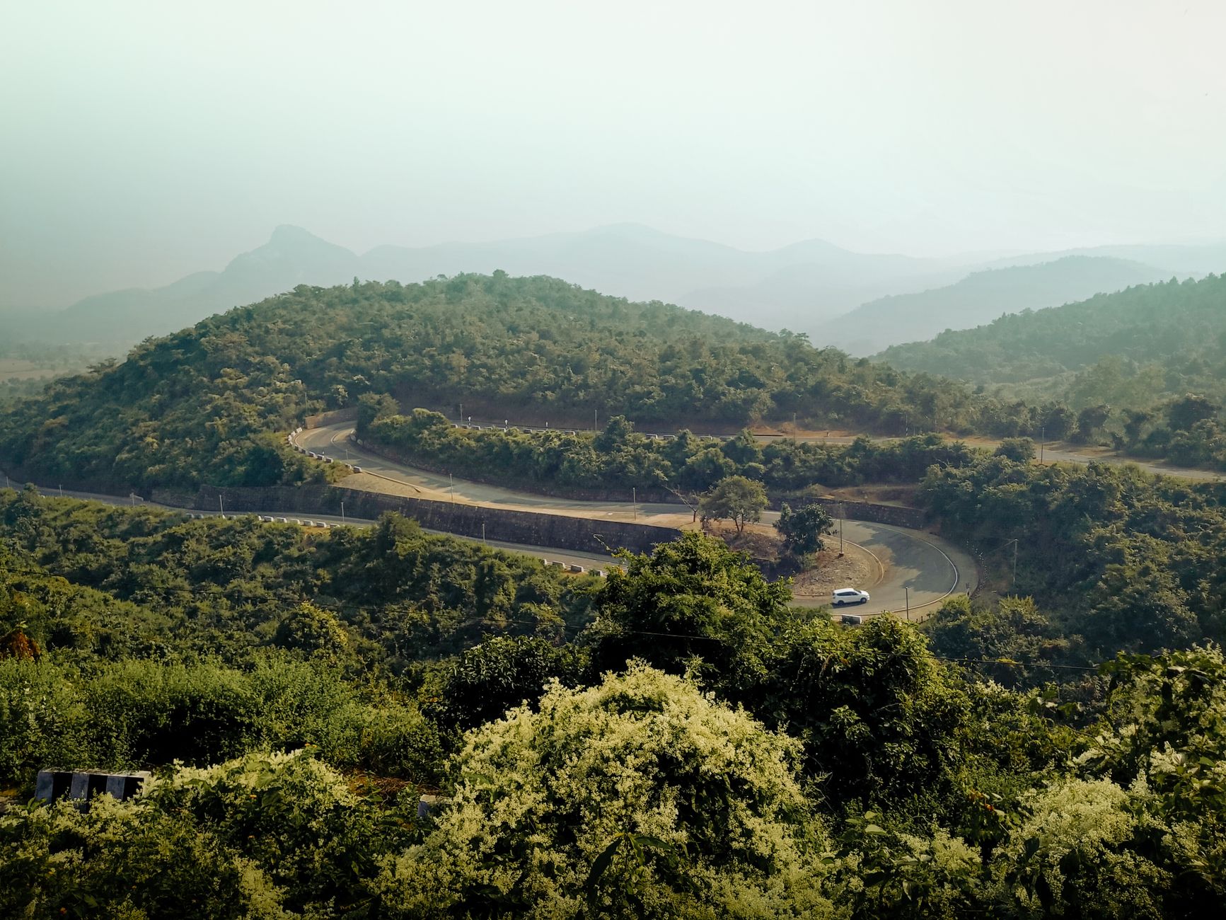 Aerial view of a winding road through lush green hills in Purulia, India. Ideal travel and nature concept.