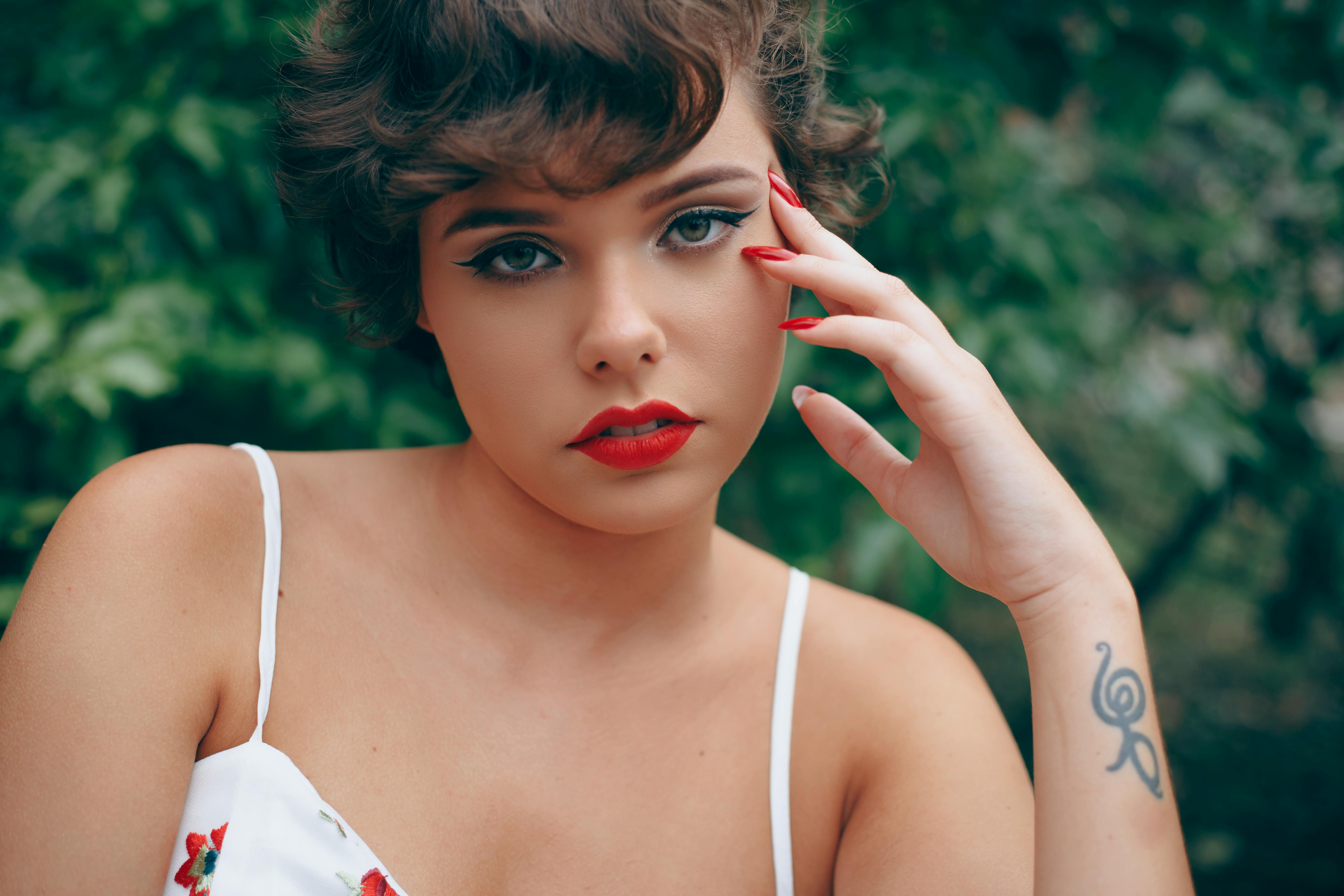 一位女性的特写肖像，红唇醒目，纹身富有艺术感