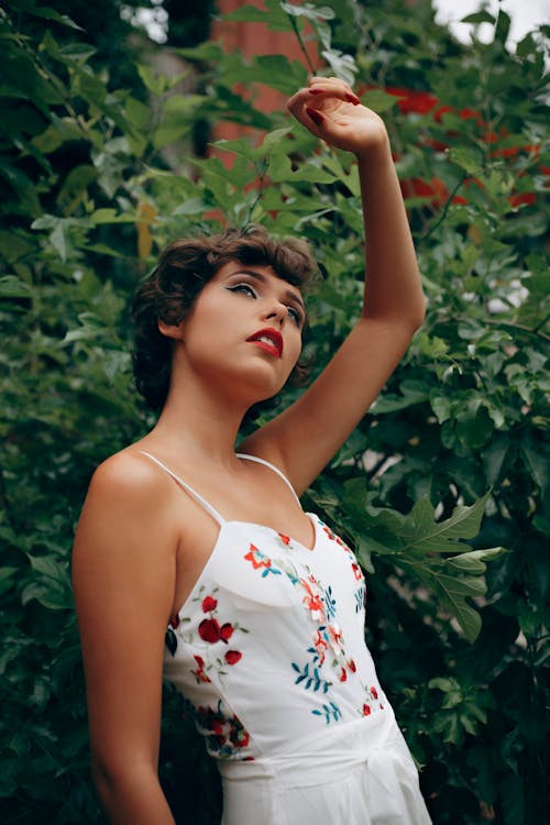 Free Женщина стоит возле растения, поднимая левую руку над головой Stock Photo