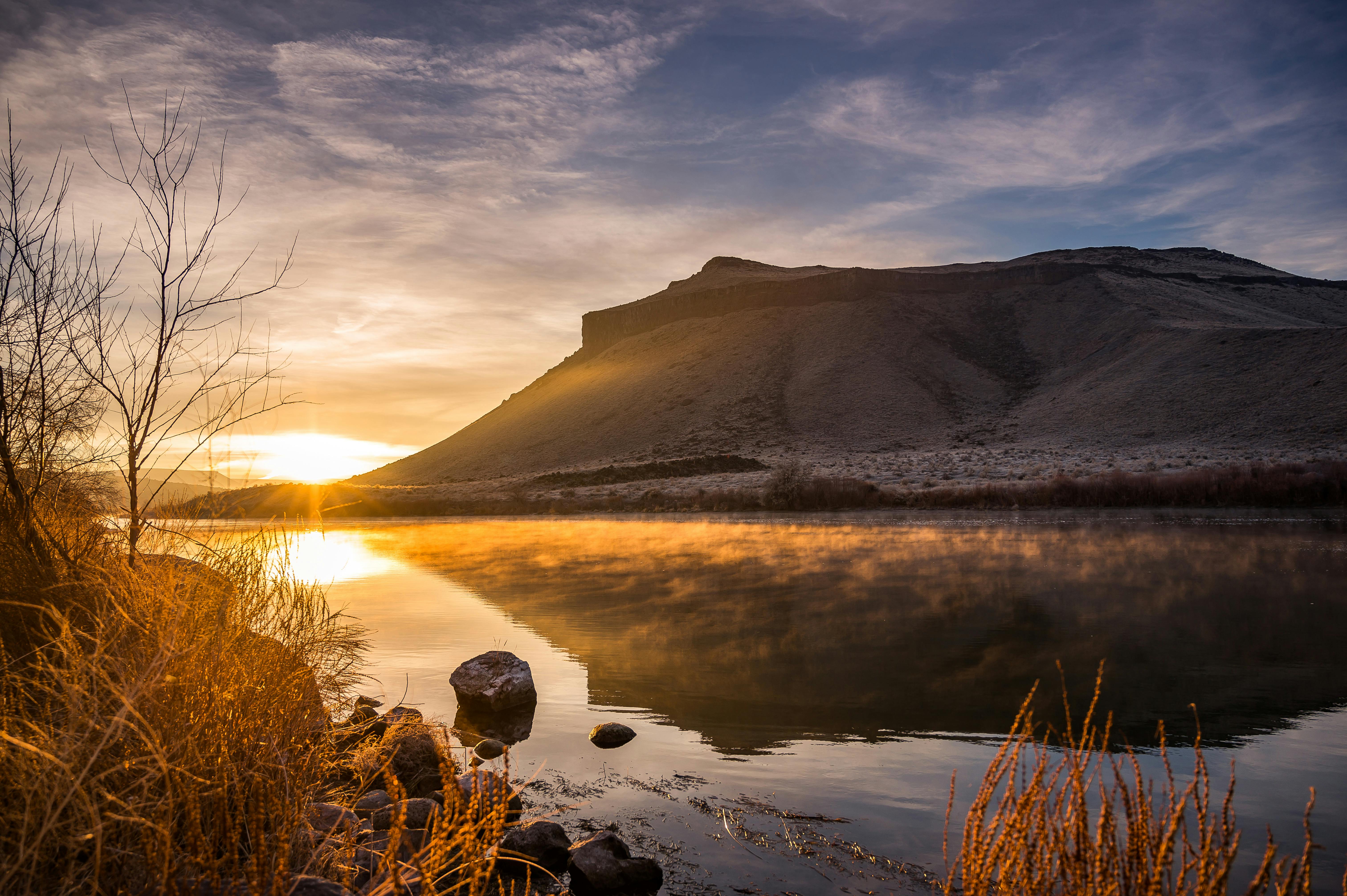 宁静的湖泊倒映着雄伟的山影，映衬着令人叹为观止的日出