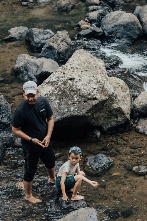 Free Father and son enjoying leisure time by a rocky river in summer. Stock Photo